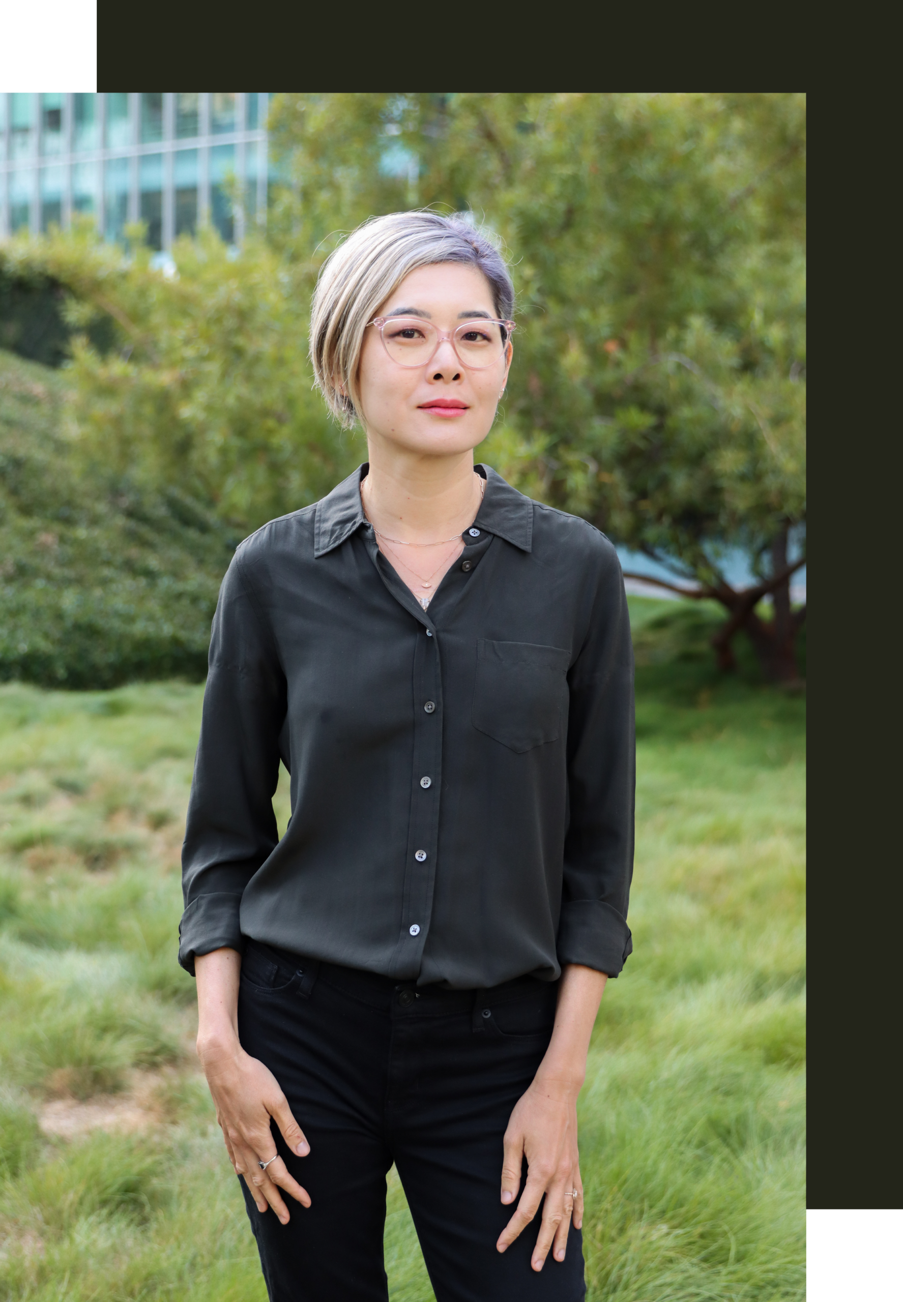 Eileen Chao, MA, intimacy coach and surrogate partner in San Francisco, standing outdoors with soft green foliage behind her